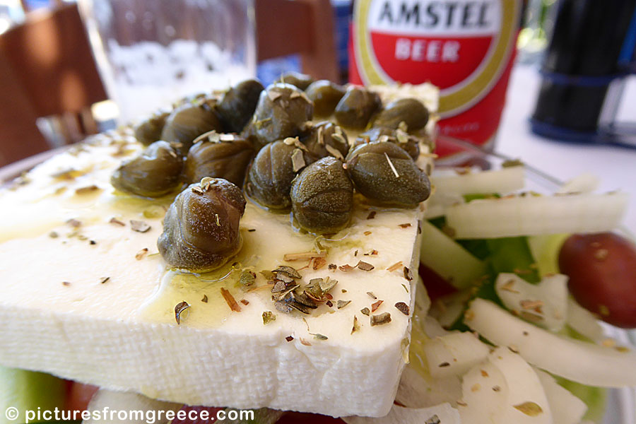 A Greek salad always contains feta cheese, olives, onion, tomatoes, pepper and oregano. Sometimes it is also comes with capers.